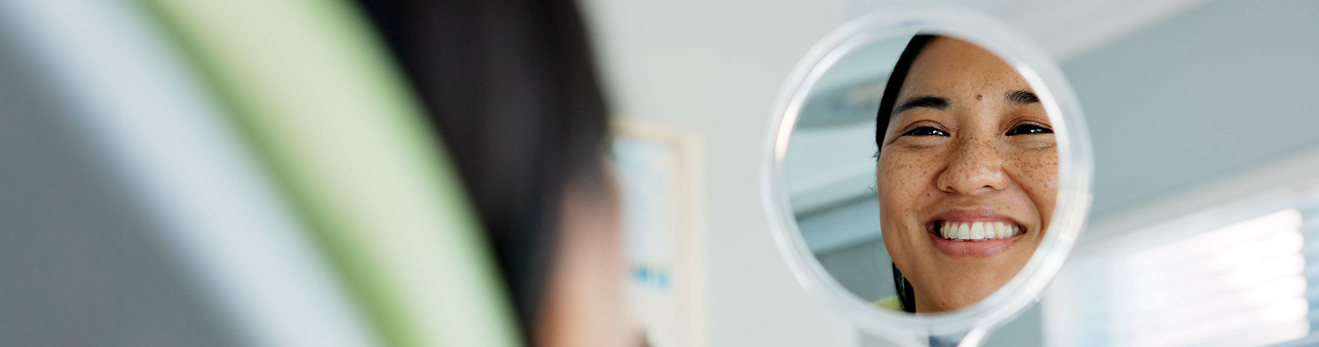 A person smiling at their own reflection in a circular mirror.