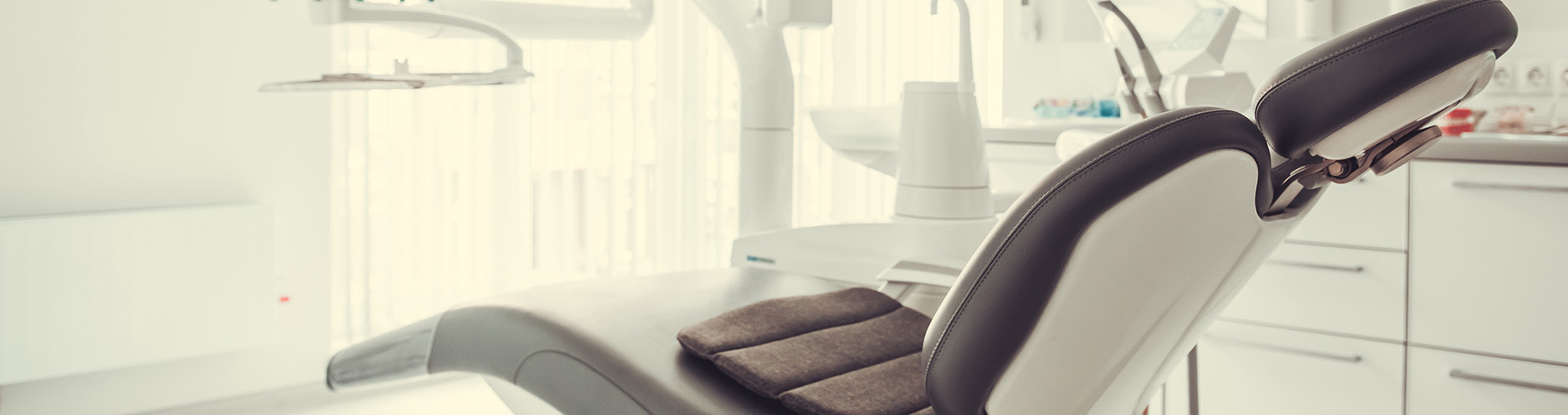 The image shows a group of people, possibly professionals given their attire and the setting that appears to be an office or professional environment. They are gathered around a table with a laptop on it, engaged in what seems to be a discussion or meeting.